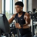 Atleta no elíptico profissional em academia iluminada por luz natural
