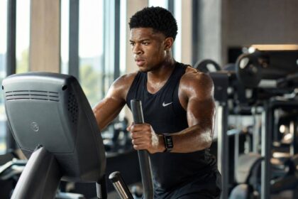 Atleta no elíptico profissional em academia iluminada por luz natural
