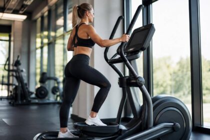 Atleta usando elíptico profissional em academia moderna com luz natural e fundo desfocado